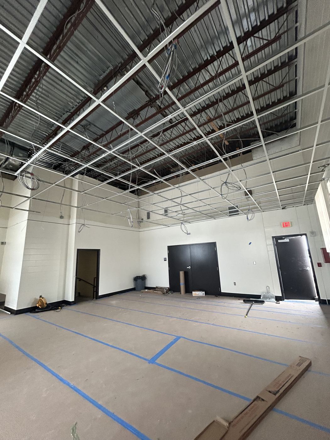New ceiling grid installed and wiring dropped, floor protection still in place.