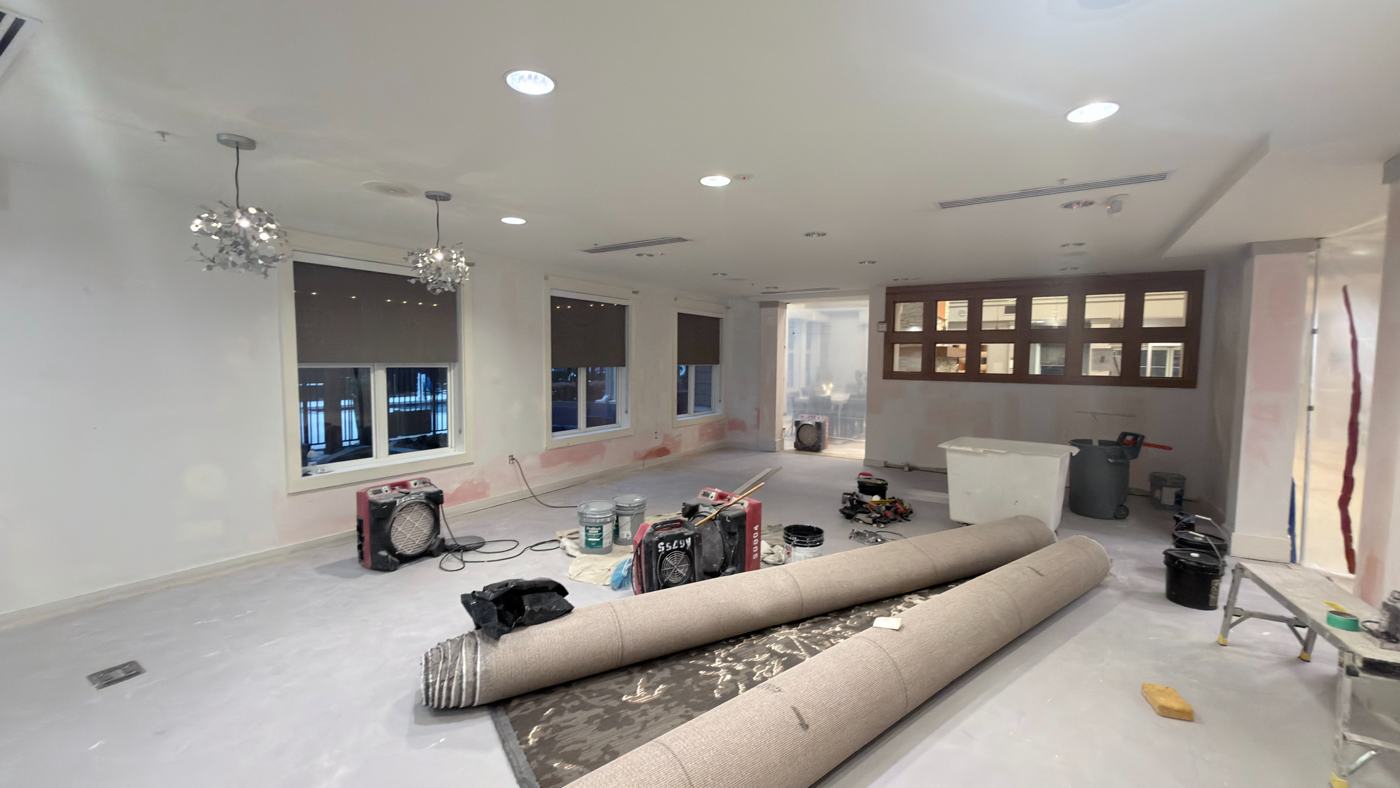 Hotel meeting room mid-renovation: walls patched and primed, new carpet rolled and waiting, air scrubbers running.
